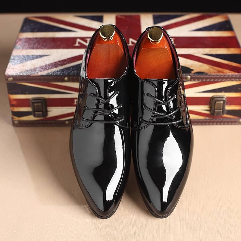 Elegance Defined: Men's Classic Black Leather Slip-On Dress Shoes 2 Shiny Black Leather Dress Shoes With Polished Finish, Stylish Formal Footwear For Men, Placed On A Wooden Table With A Vintage British Flag-Themed Box Background.