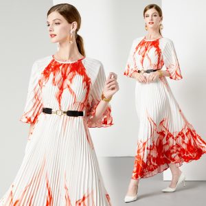 A woman wearing a white dress with red abstract patterns and a black belt, standing in a neutral background.