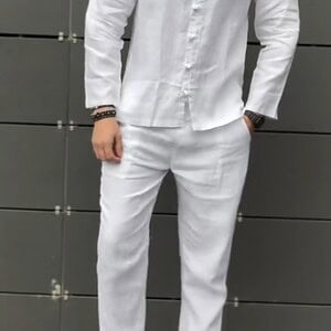 Man wearing a white linen shirt and pants with white sneakers.