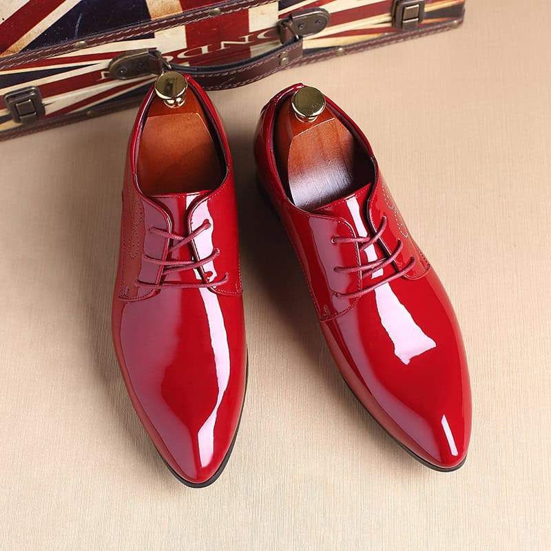 Elegance Defined: Men's Classic Black Leather Slip-On Dress Shoes 8 Bright Red Polished Men'S Dress Shoes With Laces, Stylish And Formal Footwear, Displayed On A Wooden Surface With A Vintage Suitcase In The Background.