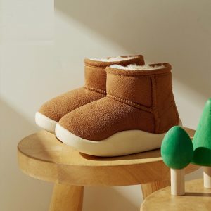 Soft brown baby shoes with white soles on wooden stand for infants and toddlers, cozy and warm footwear, perfect for cold weather and indoor use, featured in a nursery or playroom setting.