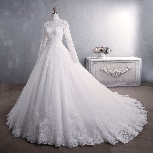 A white lace wedding dress featuring long sleeves and a full skirt with intricate detailing.