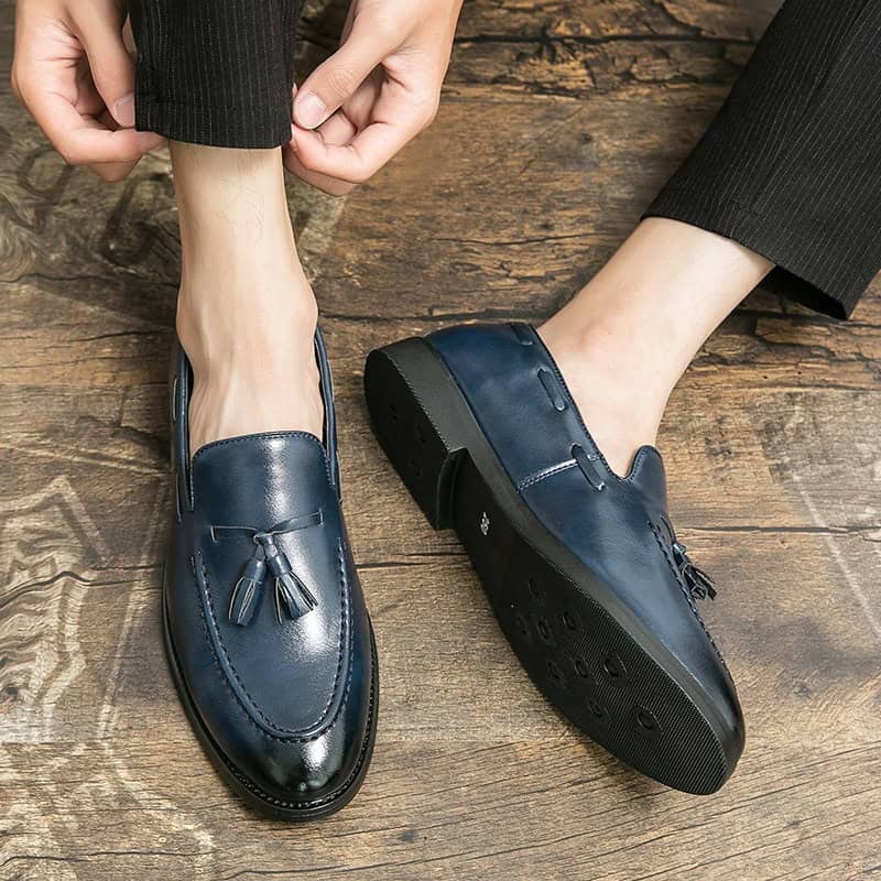 Timeless Elegance: Stylish Tassel Leather Shoes for Today's Gentleman 4 Polished Navy Blue Leather Loafers With Tassels, Stylish And Comfortable Men'S Footwear Ideal For Business Or Casual Wear, Placed On A Rustic Wooden Floor.