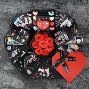 Heart-shaped gift box containing red roses and decorative cards arranged around it.