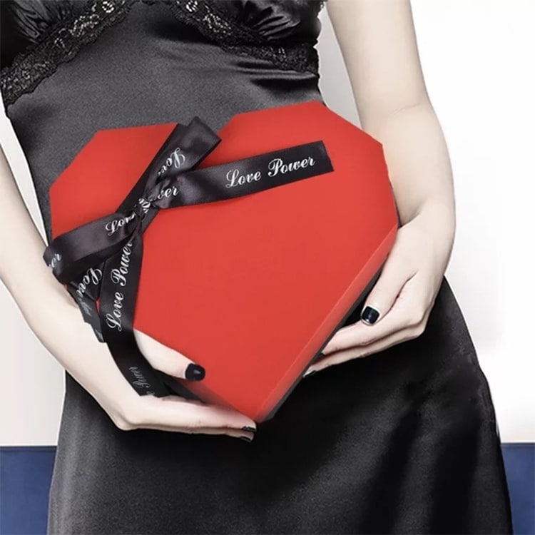 Surprise Explosion Heart-Shaped DIY Handmade Photo Album & Gift Box 9 A Red Heart-Shaped Gift Box Held By A Person Wearing A Black Dress, Tied With A Black Ribbon That Says 'Love Power'.