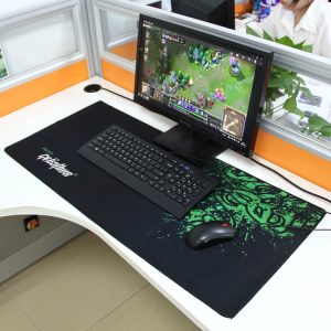 Gaming setup with desktop monitor, keyboard, and mouse on a large anti-slip gaming mouse pad in an office environment, suitable for online gaming and esports.