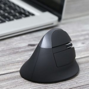 Wireless ergonomic computer mouse on wooden desk with laptop in background, highlighting modern office accessories for productivity.