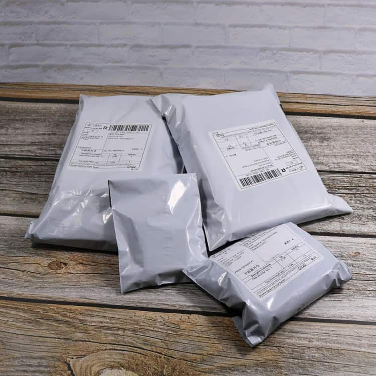 Waterproof Dark Grey Plastic Bags Roll - 55x65cm, 100 Thick Express Bags 6 Poly Mailer Packages For Shipping And Delivery, Sealed And Labeled, On Rustic Wooden Surface.