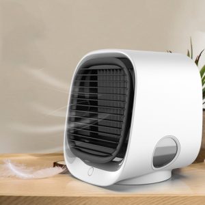 White compact portable air cooler with a front grille and control button on a wooden surface.