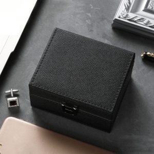 Luxury black jewelry box with textured finish on dark surface at desk, close-up, elegant storage for jewelry and accessories, premium gift box for special occasions.