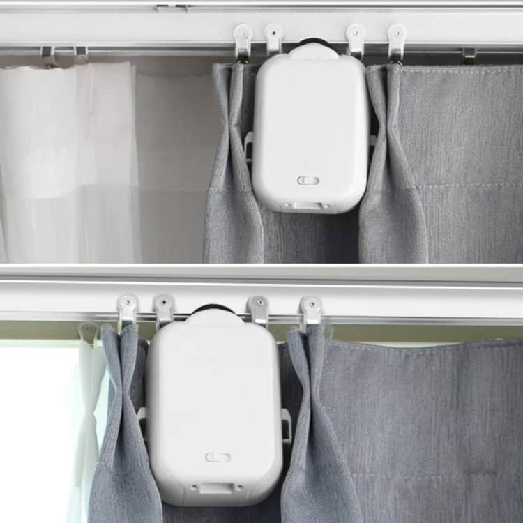 Revolutionize Your Home with X101 Smart Curtain Machine & Remote Control 2 Automated Curtain Track System With A White Motor Unit And Gray Curtains Partially Opened.
