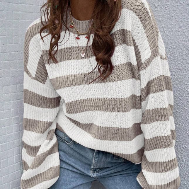 Chic Stripe Love Drop-Shoulder Sweater: Cozy Knit Fashion Statement 1 Strawberry Blonde Woman In Beige And White Striped Sweater With Layered Necklaces Standing Outdoors.