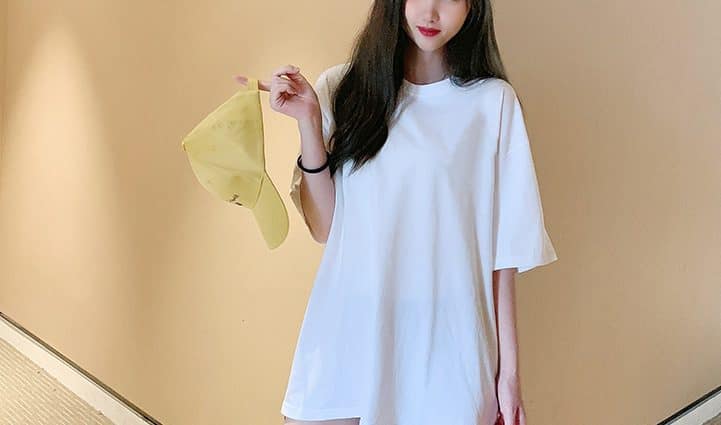 Classic Round Neck Drop Shoulder T-Shirt - Comfort meets Style! 2 A Model Posing In A White Oversized T-Shirt While Holding A Yellow Cap.