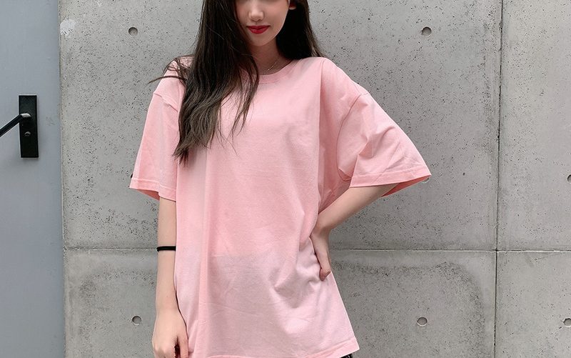 Classic Round Neck Drop Shoulder T-Shirt - Comfort meets Style! 3 A Young Woman Wearing A Light Pink Oversized T-Shirt, Posing With One Hand On Her Hip.