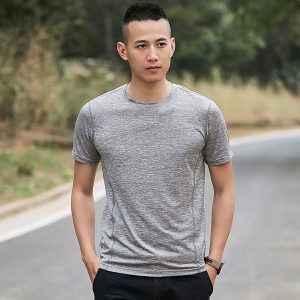 Smooth gray athletic t-shirt worn by a young man outdoors on a paved street, showcasing casual activewear for men.