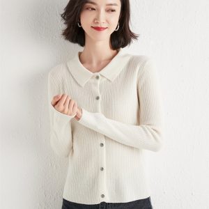 A woman wearing a white ribbed cardigan with a collar and buttons, posing with a slight smile.