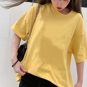 A Person Wearing A Yellow Oversized T-Shirt With A Black Bag And Black Pants.