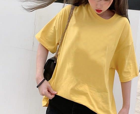 Classic Round Neck Drop Shoulder T-Shirt - Comfort meets Style! 1 A Person Wearing A Yellow Oversized T-Shirt With A Black Bag And Black Pants.