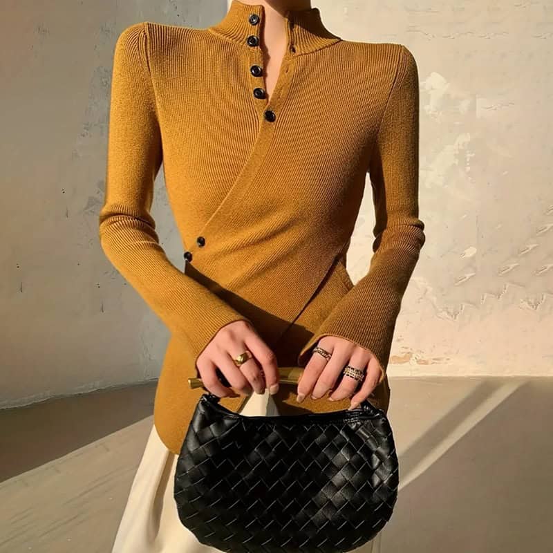 Chic Sweet & Spicy Stand Collar Cross Button Sweater for a Stylish Look 1 A Long Sleeve Mustard Sweater With A Buttoned Front And A Black Woven Handbag Held By A Person.