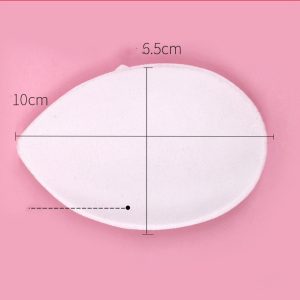 White makeup sponge with measurements on pink background, cosmetic beauty blending tool for face and foundation application.