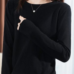 A Person Wearing A Black Long Sleeve Top With A Round Neckline And A Pearl Necklace.