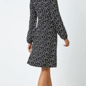 Stylish black and white patterned midi dress with long sleeves, perfect for casual or semi-formal occasions.