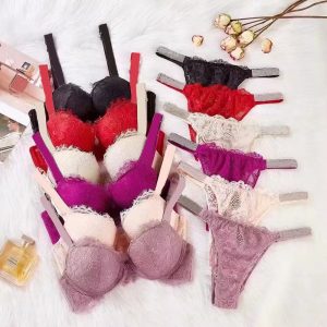 Colorful Lace Bras In Black, Red, White, Pink, Purple, And Mauve Laid Out On A White Surface With Flowers And Perfume For A Stylish Lingerie Display.