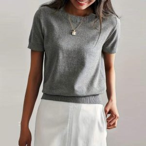 Woman wearing a gray short-sleeve sweater with a round neckline and a fitted bottom hem.
