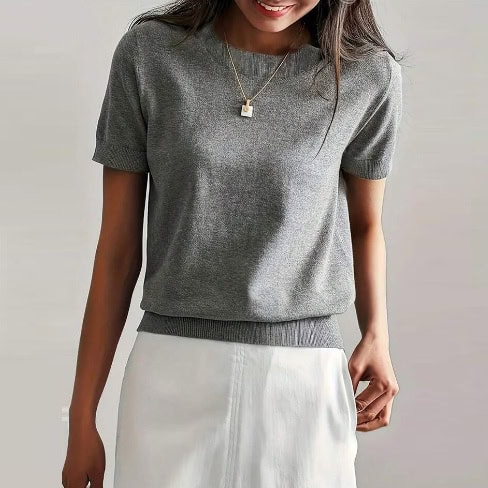 Solid Color French Short Sleeve Sweater - Simple Round Neck Charm 1 Woman Wearing A Gray Short-Sleeve Sweater With A Round Neckline And A Fitted Bottom Hem.