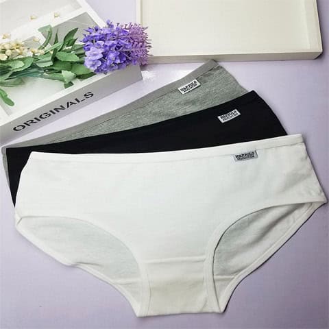 Girl's Gray, White & Black Solid Color Underwear Set - Comfort & Style Combined 3 Soft Cotton Women'S Underwear In White, Black, Gray, And Beige, Laid Out On A Pastel Surface With Decorative Flowers And A Book, Showcasing Comfortable, Breathable Everyday Lingerie Options.