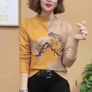 Youthful Woman Wearing Stylish Beige And Mustard Sweatshirt With Tree Graphic, Posing Indoors For Fashion And Casualwear Showcase.