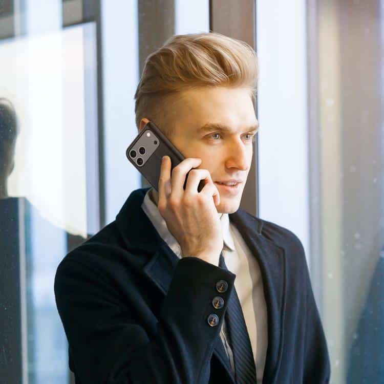 DUX DUCIS Hivo Series Cowhide Flip Case for iPhone 17 & 16 - Luxurious Protection 7 Phone Call, Professional Businessman Talking On Smartphone At Office Window, Modern Corporate Work Environment, Communication And Technology, Syndmart Branding.