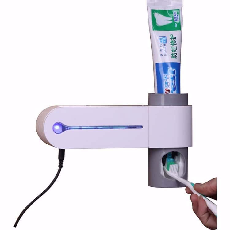 UV Toothbrush Sterilizer & Automatic Toothpaste Dispenser with Storage Holder 4 Automatic Toothpaste Dispenser Mounted On A Wall Holding A Tube Of Toothpaste, With A Toothbrush Being Placed For Automatic Dispensing. Suitable For Bathrooms And Kitchens, Promoting Hygiene And Convenience.
