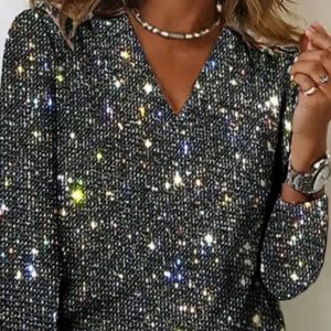 Close-up of a woman's black top with a V-neck and sparkling embellishments.