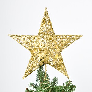 Shiny gold glitter star topper on decorated Christmas tree for holiday celebration and festive decoration.