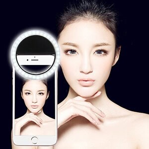 Elegant woman with flawless skin taking selfie with ring light for beauty and skincare enhancement, showcasing professional photography, skincare, and modern beauty tools.